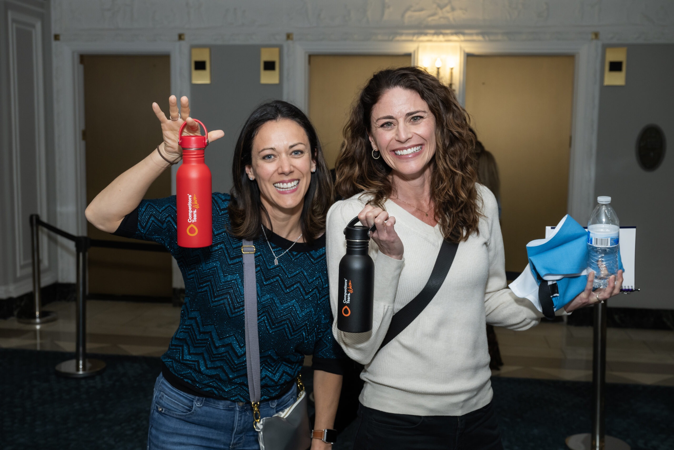 two women smiling standing holding water bottles
