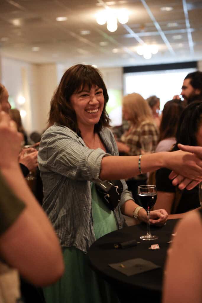 A woman smiling and shaking hands.