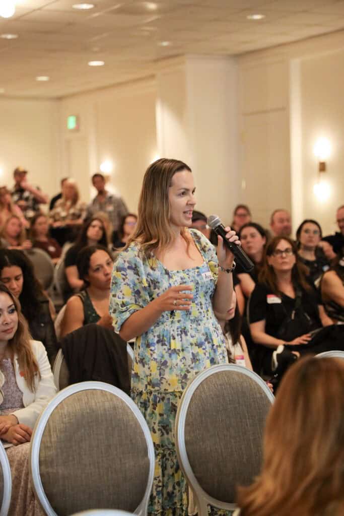 A woman in a blue floral dress asking a question.