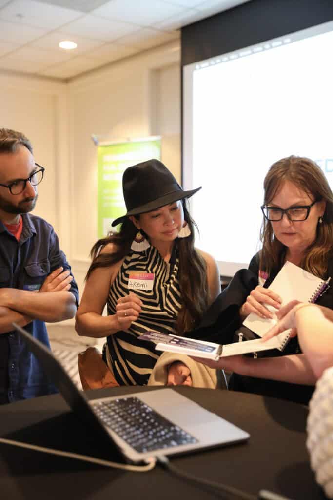 Two women and a man admiring a notebook.